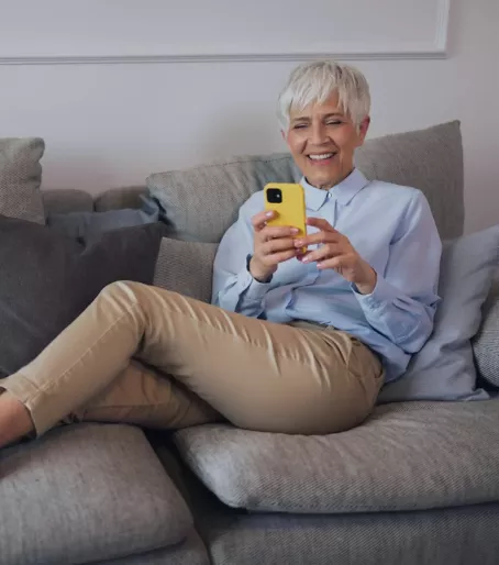 Mulher sentada no sofá usando o celular